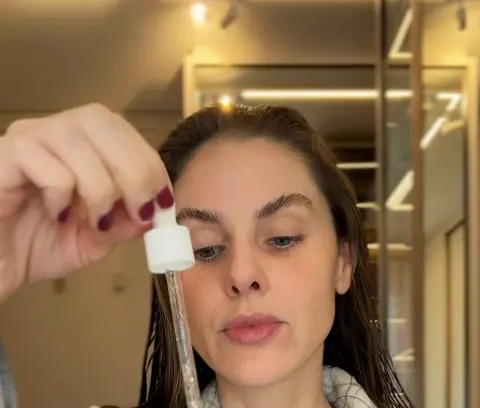 A Dra. aplicando sérum com conta-gotas, na rotina de skincare